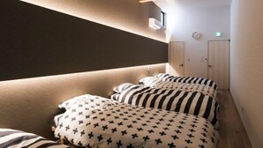 Um quarto pequeno e com pouca luz, teto inclinado, vigas de madeira e uma cama com roupa de cama listrada.