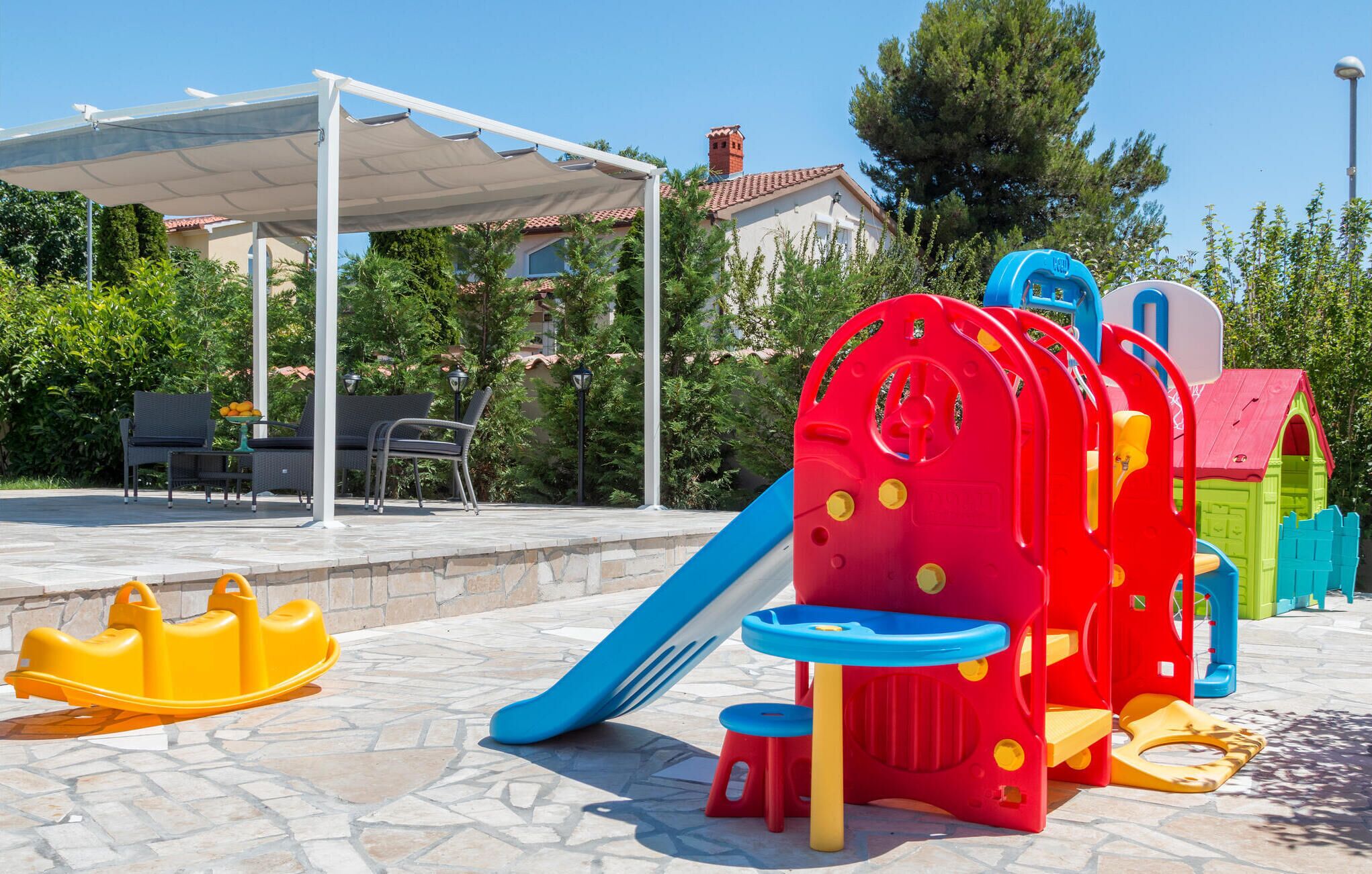 A children's play area with a slide, a small boat, and a playhouse.