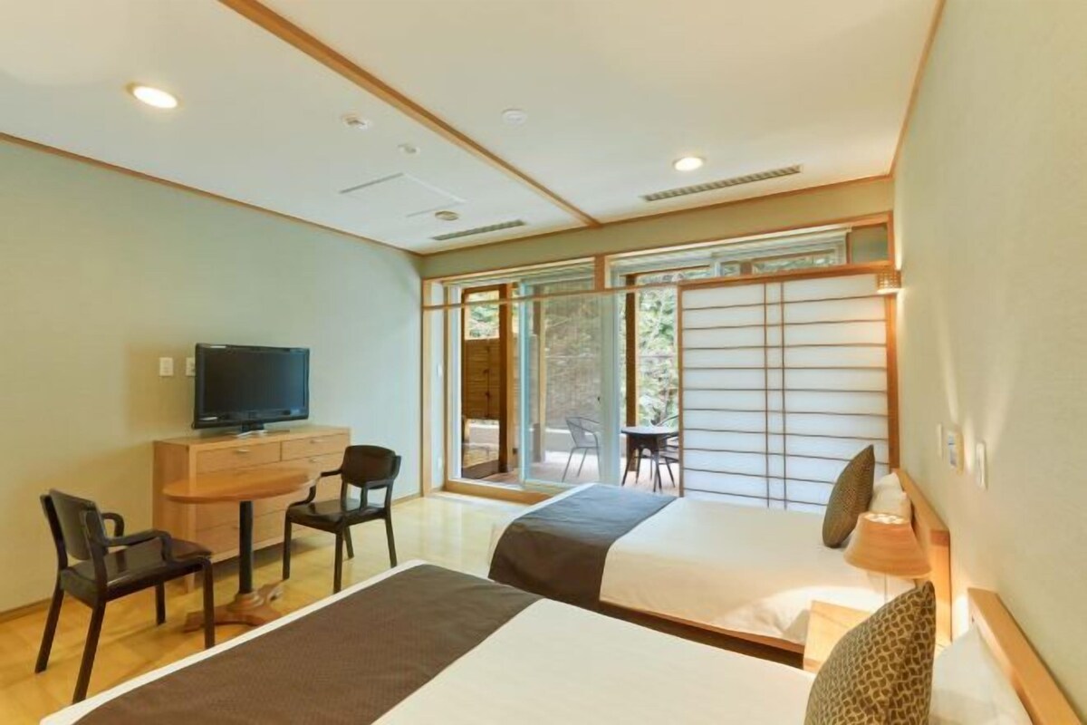 Une chambre d’hôtel avec deux lits, une télévision, un bureau et une chaise.
