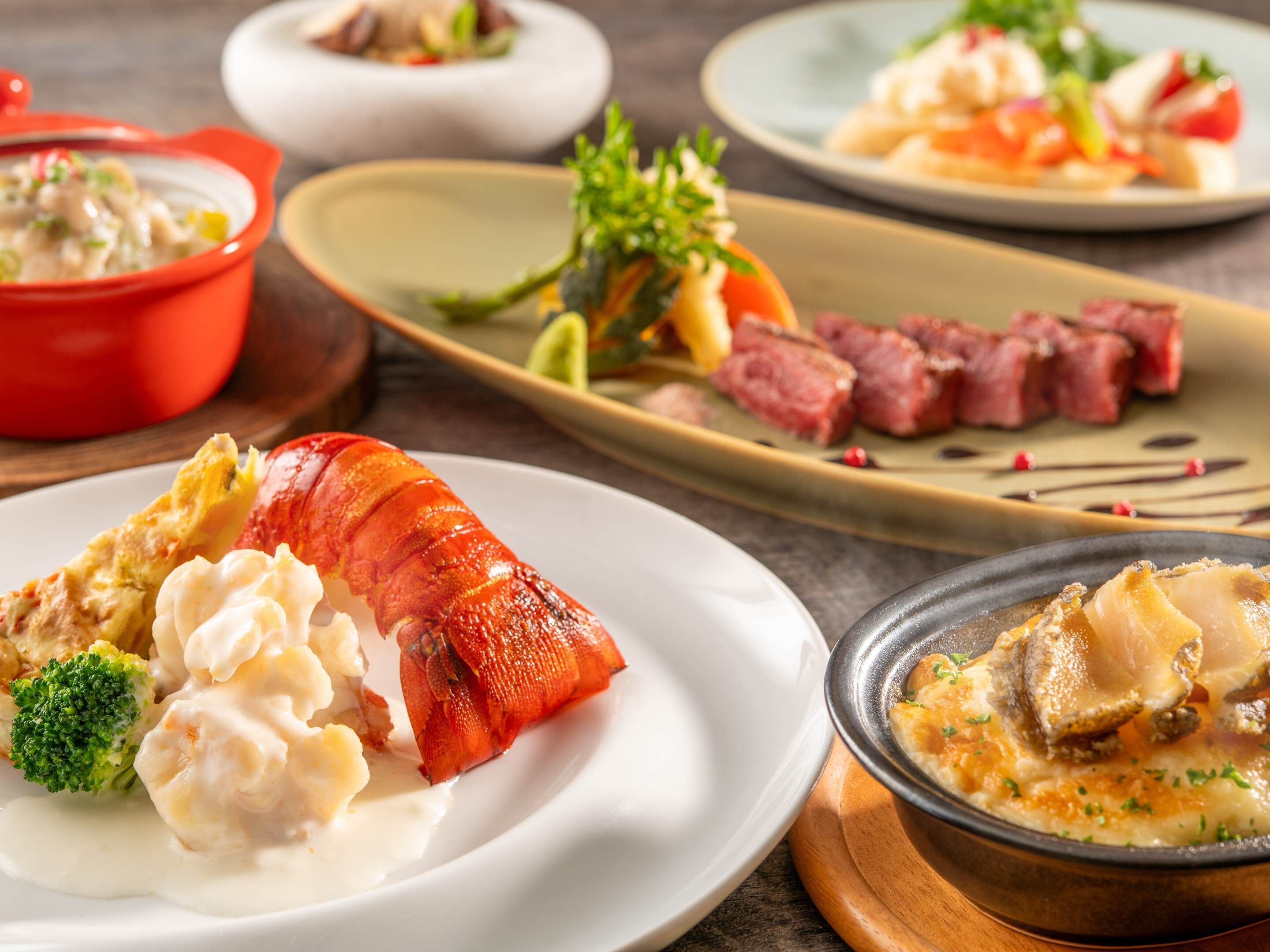 A variety of dishes including lobster, dumplings, and a soup.