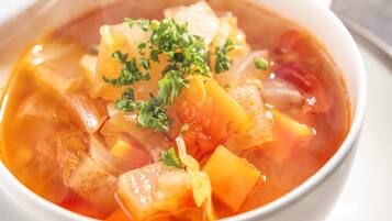 A bowl of soup with vegetables and herbs.