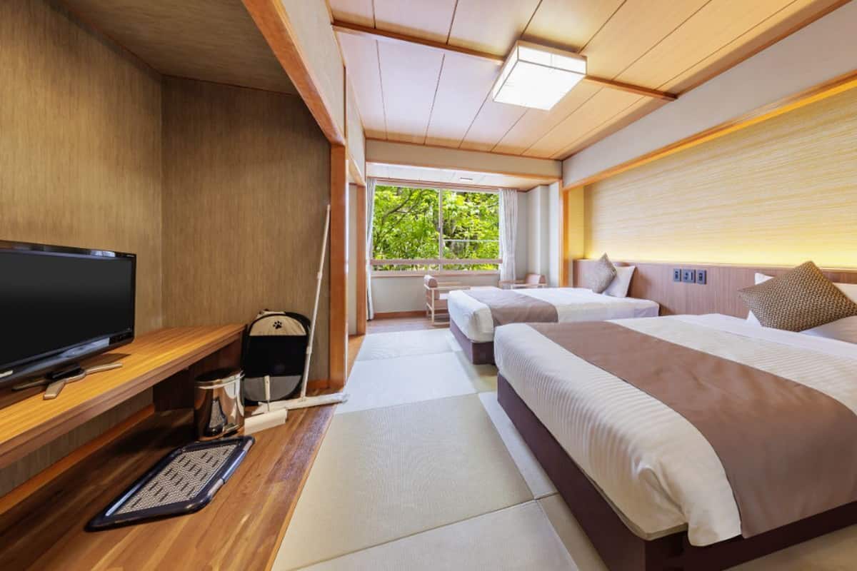 Une chambre d’hôtel équipée d’une télévision, d’un bureau et de deux lits.