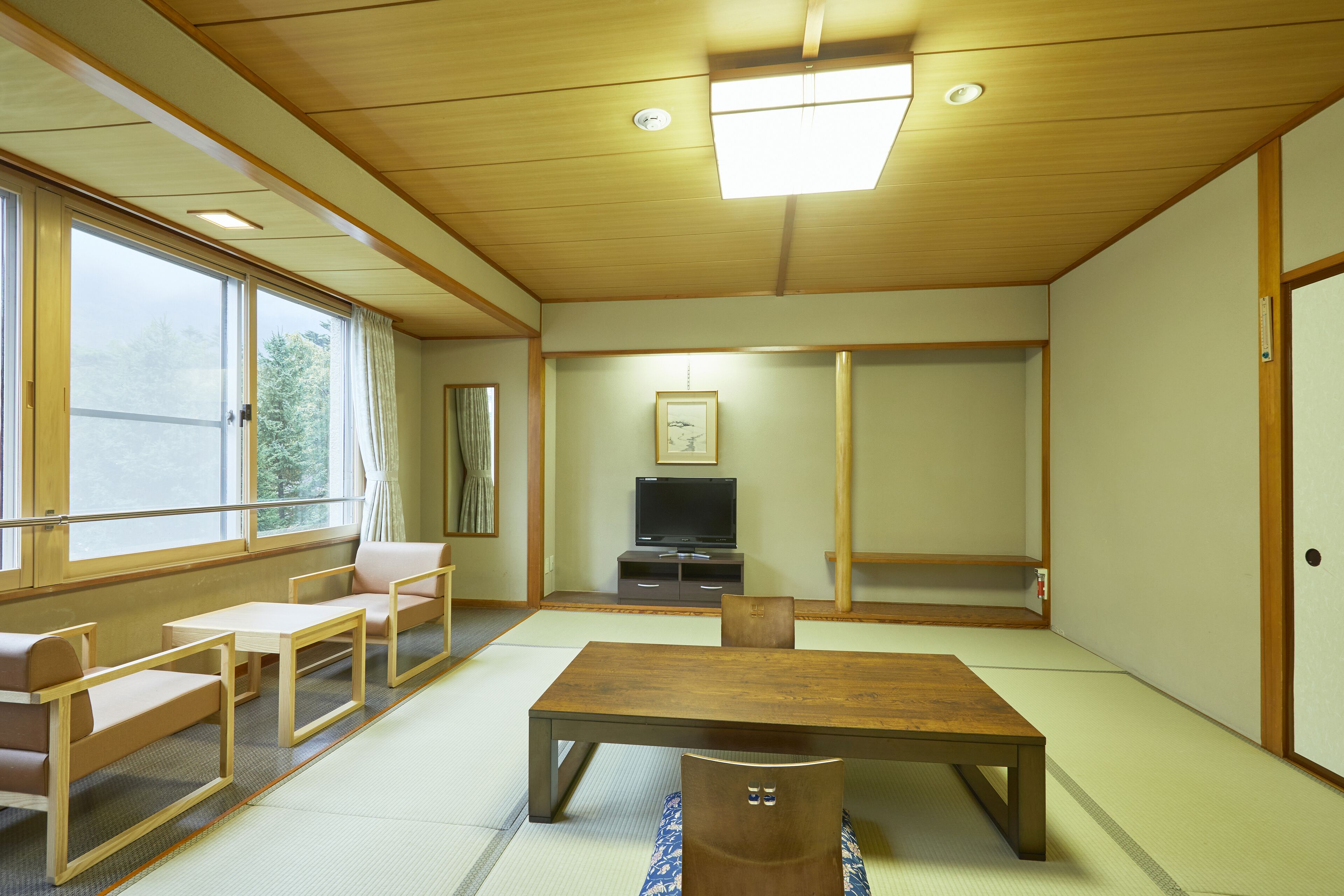 A traditional Japanese-style room with tatami flooring, a low wooden table, and seating arrangements.