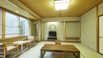 A traditional Japanese-style room with tatami flooring, a low wooden table, and seating arrangements.