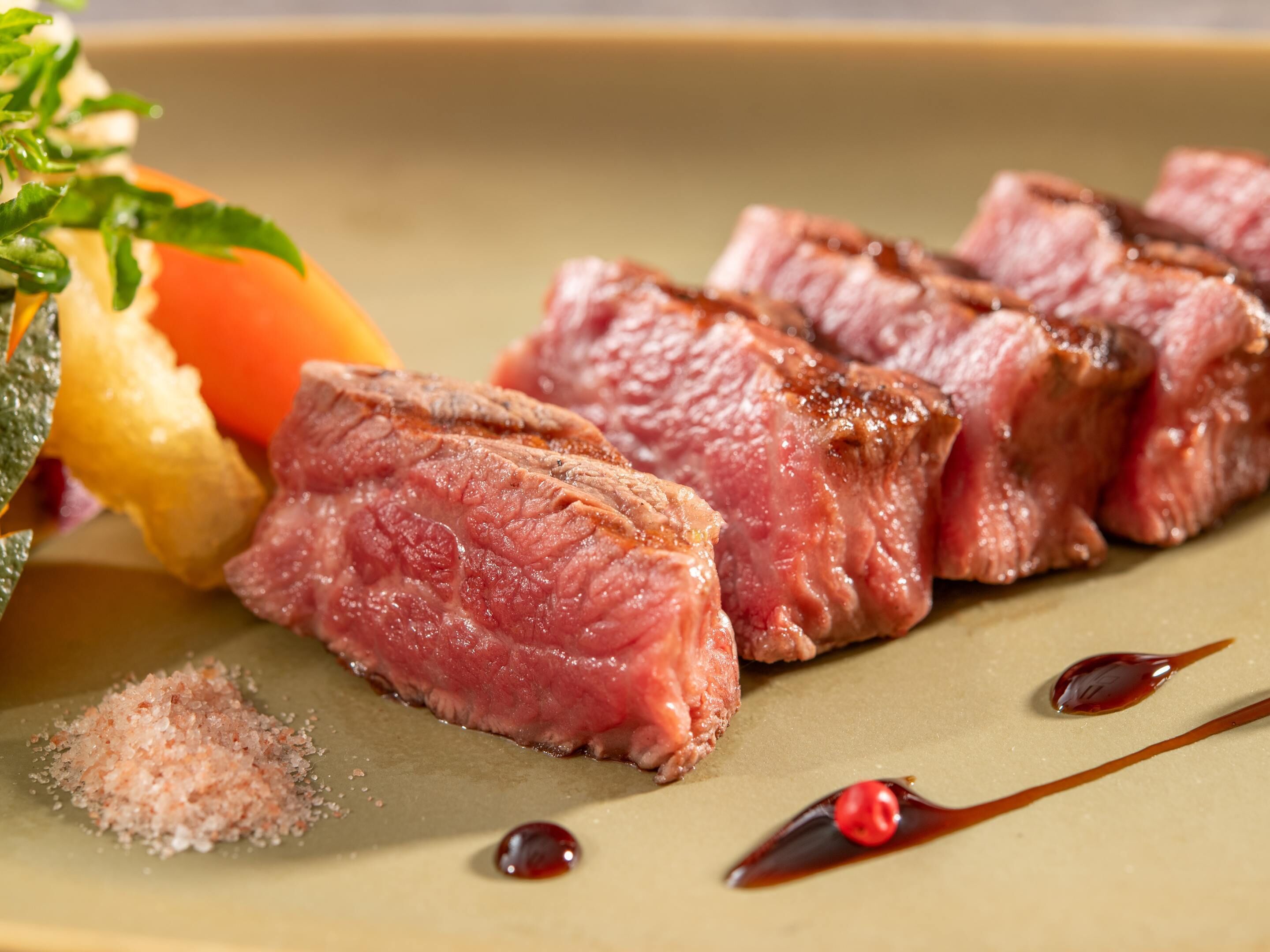 A plate with sliced meat, a tomato, and some condiments.