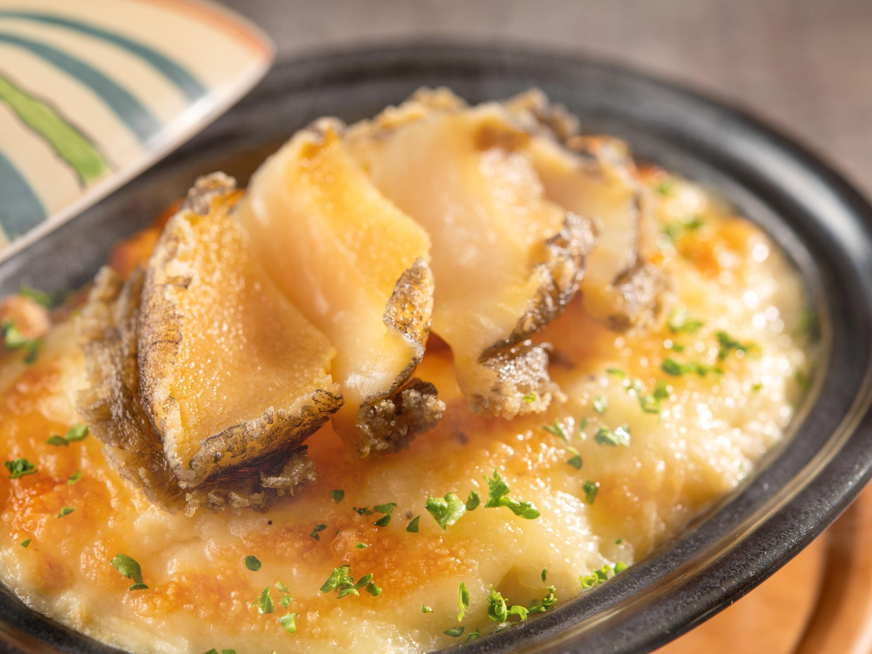 A dish with a creamy sauce, garnished with herbs, served on a black plate.