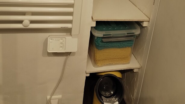 A bathroom with a white towel rack, a white shelf with storage bins, and a white wall. - APARTMENT DUPLEX SUPER SAUZE 1700 (LE SUPER SAUZE, Enchastrayes)