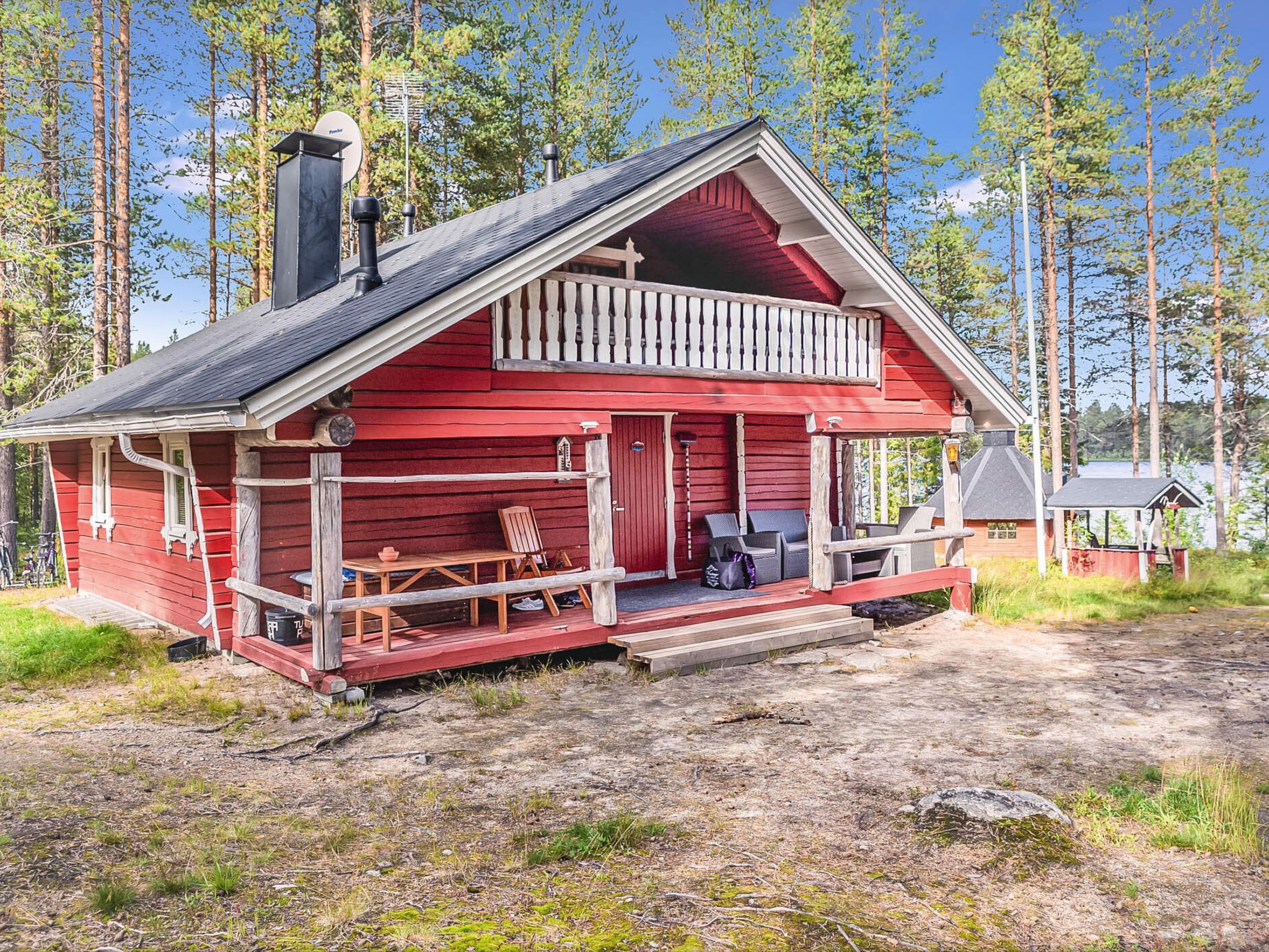 Une cabane rouge avec un porche, une cheminée et une petite terrasse.