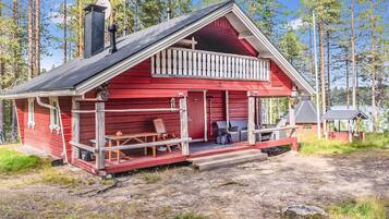 Une cabane rouge avec un porche, une cheminée et une petite terrasse.