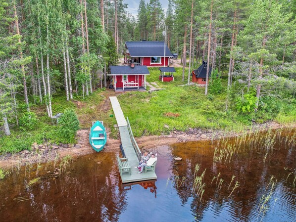 A lakeside cabin with a dock, surrounded by dense forest.