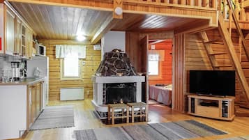 A cozy cabin interior with a kitchen, a fireplace, a television, and a staircase.