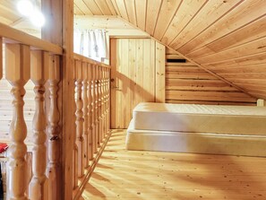 Een houten interieur met een schuine kap, een matras en een houten leuning.