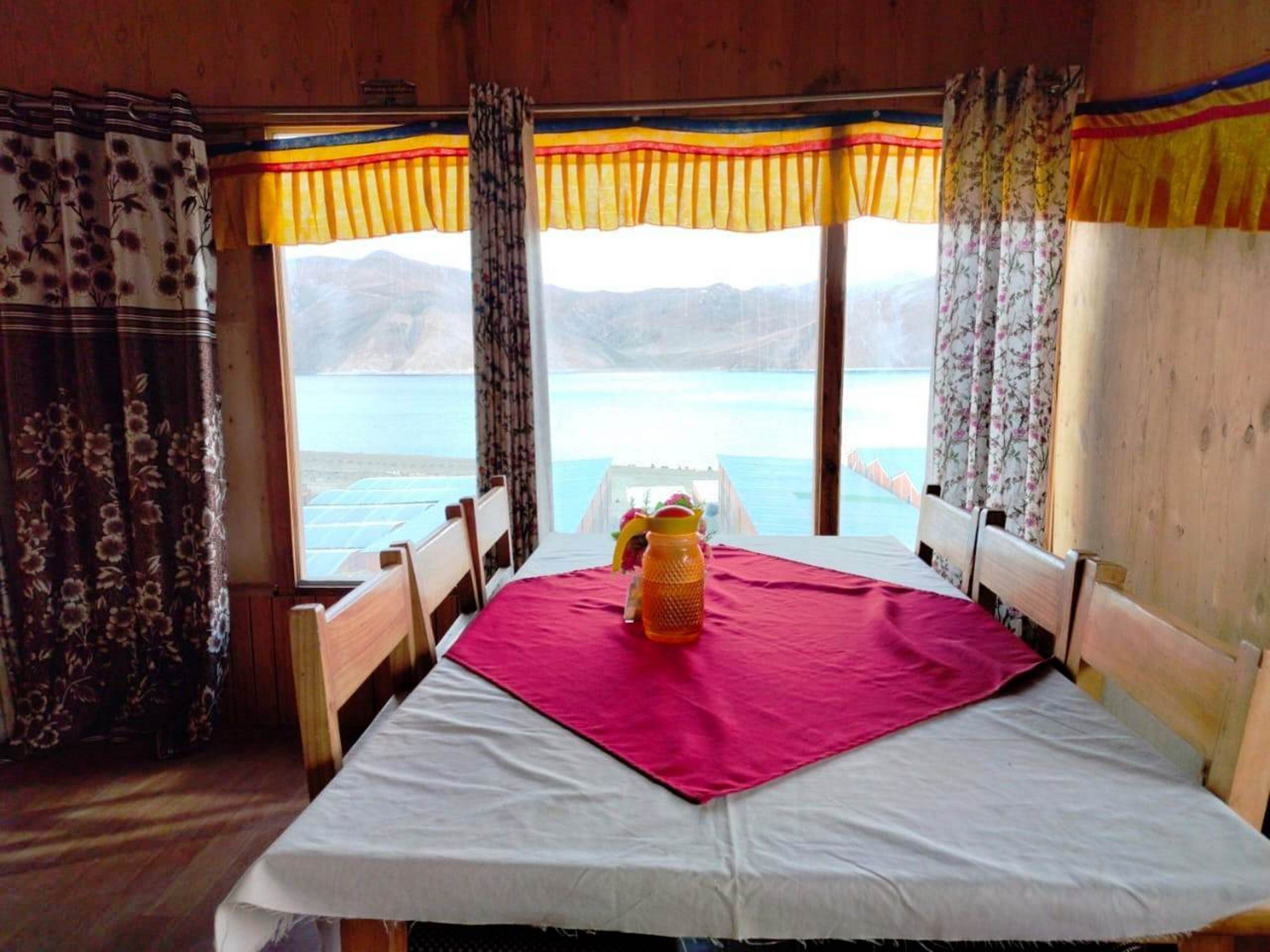 A room with a bed, wooden headboards, and a table with a pink tablecloth.