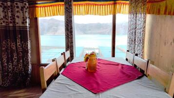 A room with a bed, wooden headboards, and a table with a pink tablecloth.
