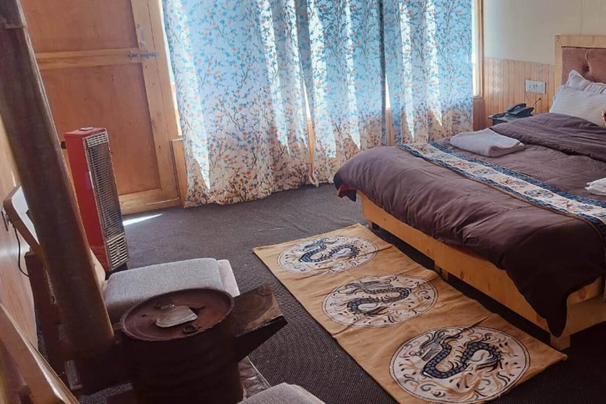 A bedroom with a wooden bed, floral curtains, and a decorative rug.