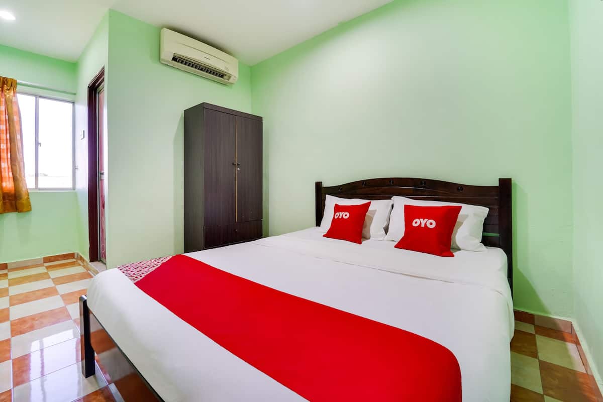 A neatly made bed with a red and white bedspread, a wooden headboard, and two pillows with the word "OYO" on them.