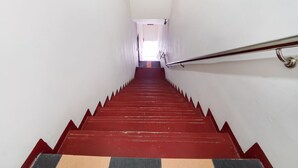 A staircase with red steps and a metal handrail, leading to a bright area at the top. - Oyo 44058 Motel Sre Bayam (Kulim)