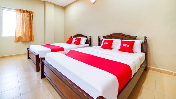 A hotel room with two beds, each with a wooden headboard, white bedding, and red accents. - Oyo 44058 Motel Sre Bayam (Kulim)