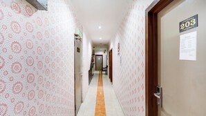 A hotel corridor with patterned wallpaper, a tiled floor, and a door labeled 203. - Oyo 44058 Motel Sre Bayam (Kulim)