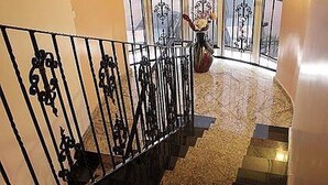 A curved staircase with ornate black metal railings and a patterned floor. - Craven Cottage Inn (Lagos)