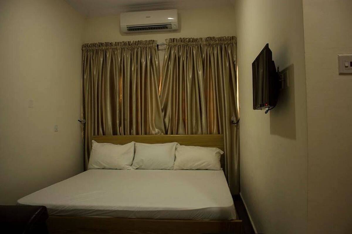 Habitación de hotel con cama, cortinas, aire acondicionado y televisor.