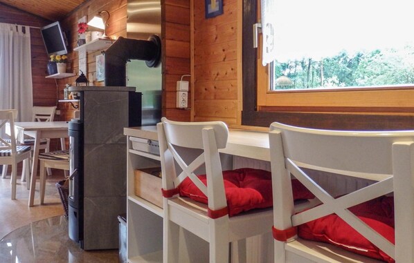 A cozy cabin interior with a dining area, a fireplace, and a window with a view of trees. - 2 bedroom awesome home in Staufenberg (Staufenberg)