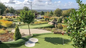 Um campo de golfe bem cuidado, com putting green, armadilhas de areia e diversas áreas ajardinadas.
