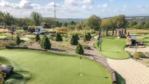 Um campo de golfe com putting green, bunkers de areia e haste de sinalização.