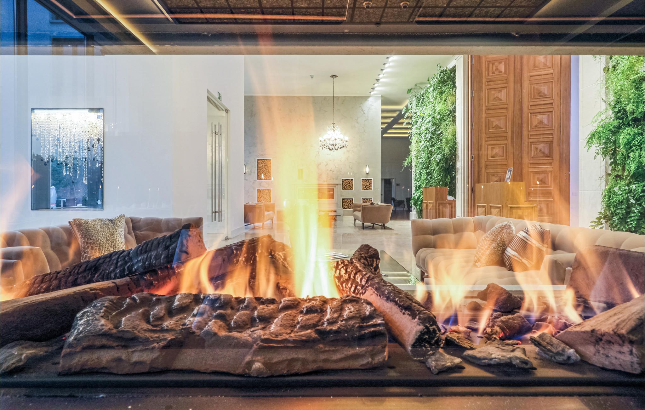 A modern living room with a fireplace, sofas, and a view of the adjacent dining area.