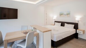 A hotel room with a bed, bedside tables, a desk, and a chair.
