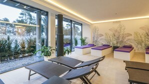 A modern spa room with large windows, reclining chairs, and a view of a snowy landscape.
