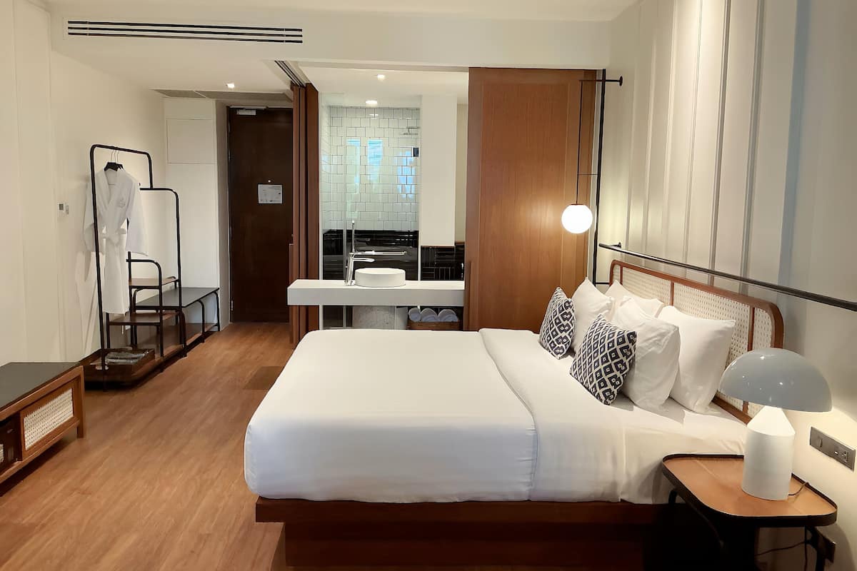 Une chambre d’hôtel avec un grand lit, une table de chevet et un bureau avec une chaise.