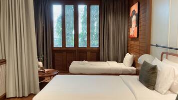 A hotel room with a large bed, a sofa, a ceiling fan, and a window with blinds.