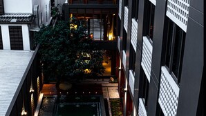 Une cour agrémentée d’un élément aquatique, entourée de bâtiments à l’architecture traditionnelle et moderne.