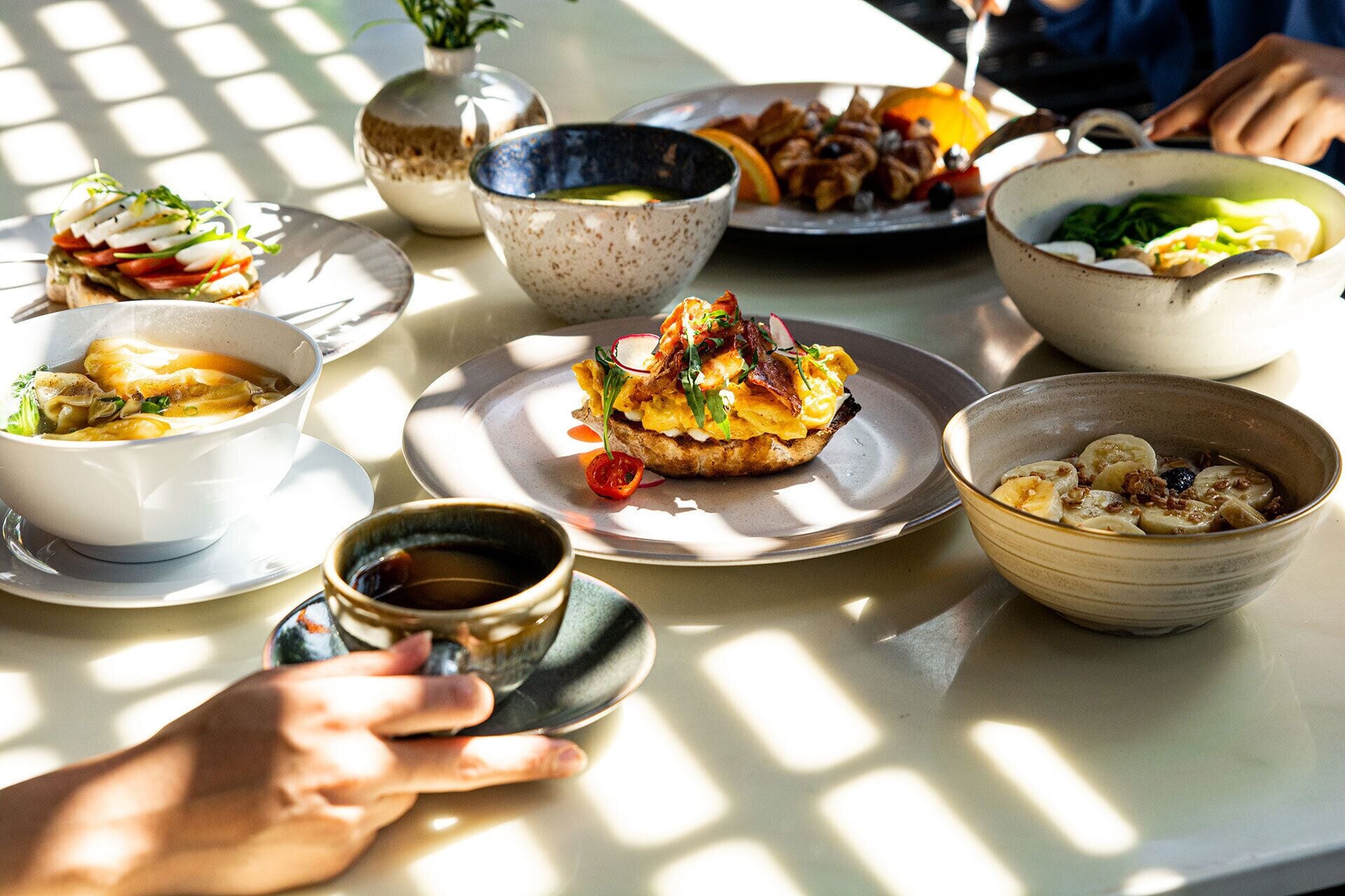 Una mesa con varios platos, incluyendo un tazón de sopa, una ensalada en un plato y un bol de fruta.