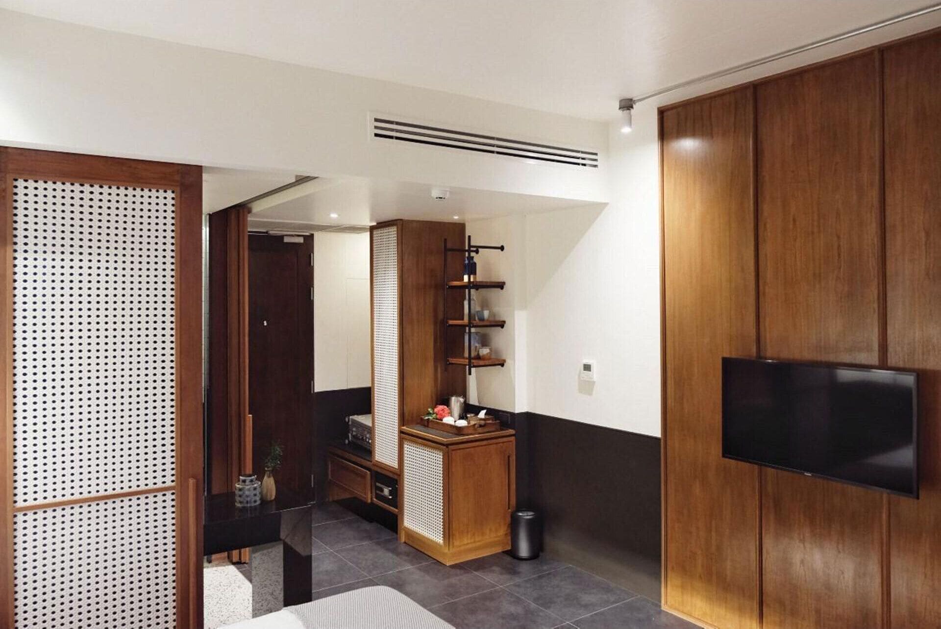 Un soggiorno moderno con un mobile in legno, una TV e un angolo cottura con lavello e scaffali.
