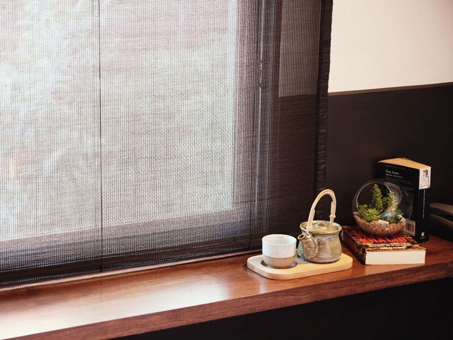 Una estantería de madera con una tetera pequeña, una taza y un libro titulado "Tom Jones" de Henry Fielding.