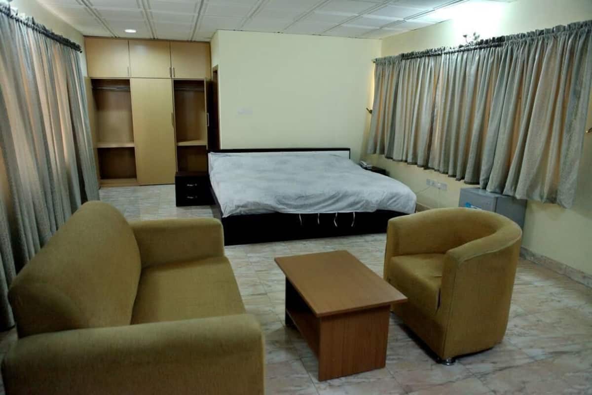 A hotel room with a bed, two sofas, a small table, and a wardrobe.