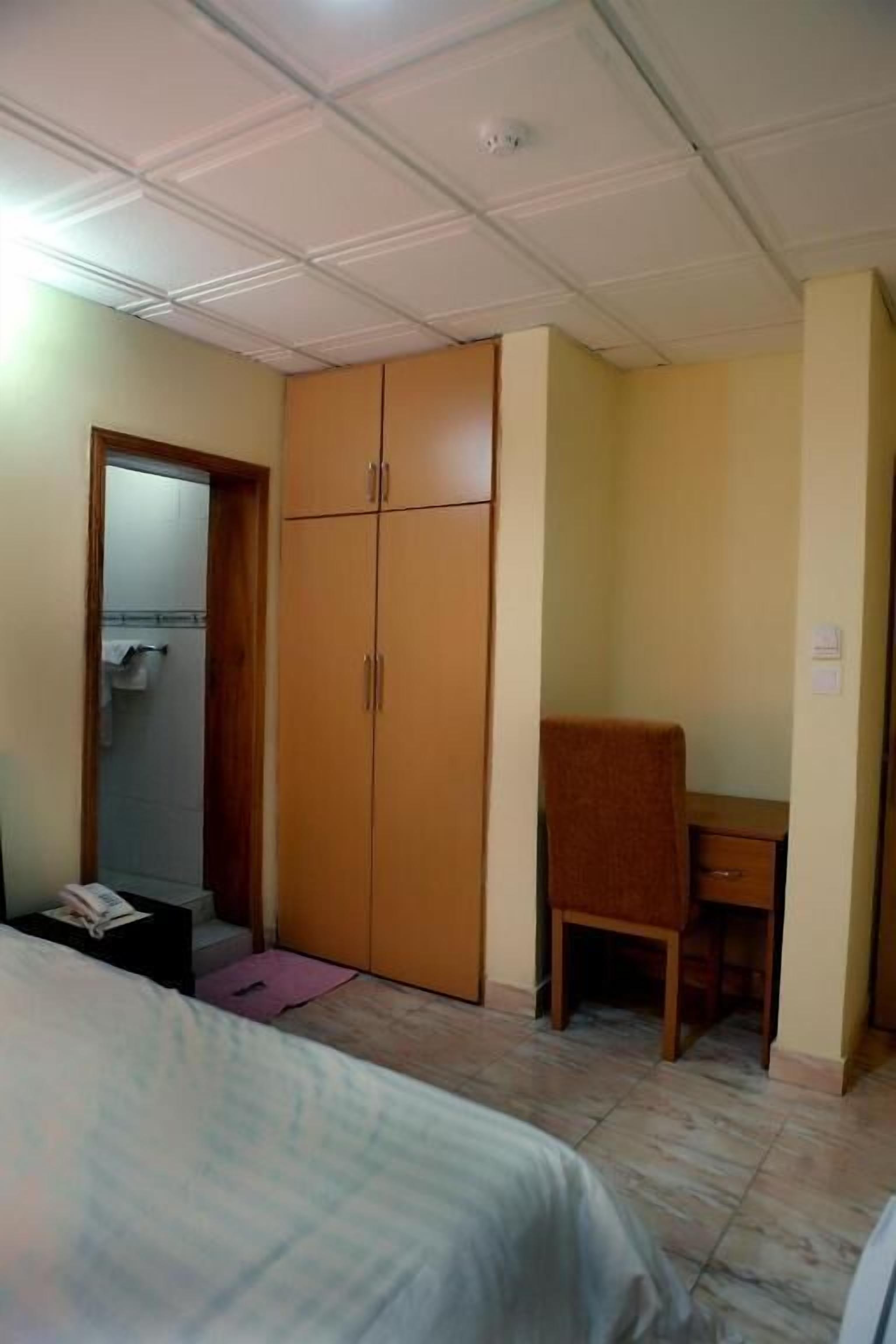 Un dormitorio con cama, escritorio, armario y puerta al baño.