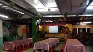 Une salle de conférence équipée de tables et de chaises, d’un écran de projection et d’un mur décoratif.