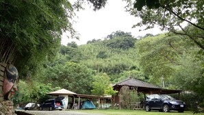 Un terrain de camping avec des tentes, une voiture et un petit bâtiment.