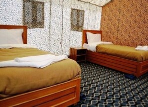 A room with two wooden beds, a patterned carpet, and a textured wall.