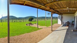A covered outdoor area with a view of a green field and mountains. - Addo Park Vista Cottages (Colchester)