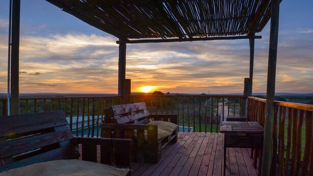 A wooden deck with benches and a table, overlooking a scenic landscape during sunset. - Addo Park Vista Cottages (Colchester)