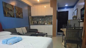 Een hotelkamer met een bed, een kitchenette, een eettafel en een stoel.