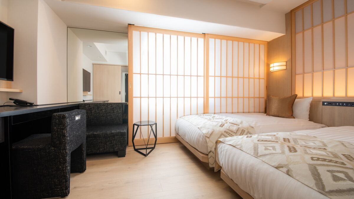 A hotel room with a bed, a desk, a chair, and a TV.