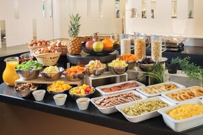 Un bufé con diversos alimentos, como frutas, verduras y carnes.