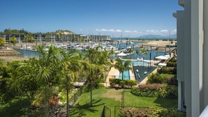 A marina with boats, a swimming pool, and lush greenery. - Beachside Apartment 10 (Nelly Bay)