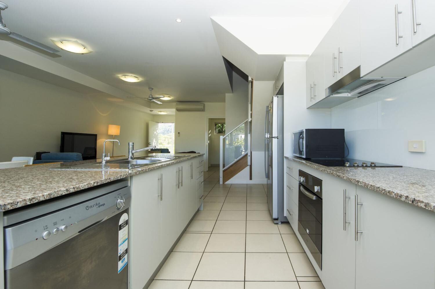 Una cocina moderna con una isla central, electrodomésticos de acero inoxidable y vista al área de estar.