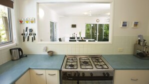 A kitchen with a gas stove, a kettle, and a window with blinds. - BrookeHaven (Arcadia)